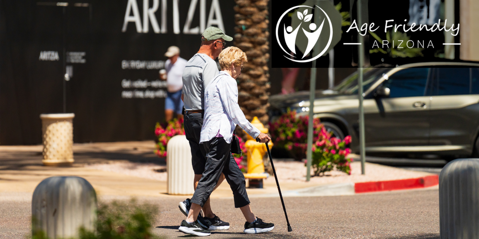 An elderly couple walking together outdoors with the Age Friendly Arizona logo
